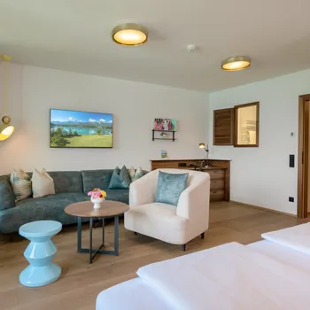 Familie Superior Modernes Hotelzimmer mit Sofa, Sessel, Schreibtisch, Fernseher und Holzfußboden